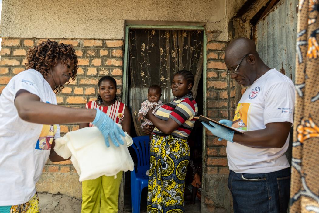A cohort of two health workers, or binôme, sensitizes a family in the Lualaba Province of the DRC on the benefits of sleeping under an insecticide-treated net (ITN) every night. One member of the binôme hands them an ITN while the other records the visit, noting that the family received one ITN for every two people as established by international standards. Credit: Arlette Bashizi. 