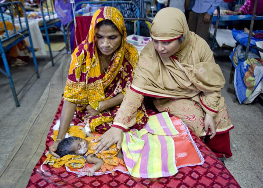 In Barisal District of Bangladesh, 2-day-old newborn (yet to be named) rests beside her maternal grandmother and Dr. Ferdousi of Save the Children. After experiencing complications during labor, the mother was referred to a hospital for the local community health worker. Photo by Jeff Holt.