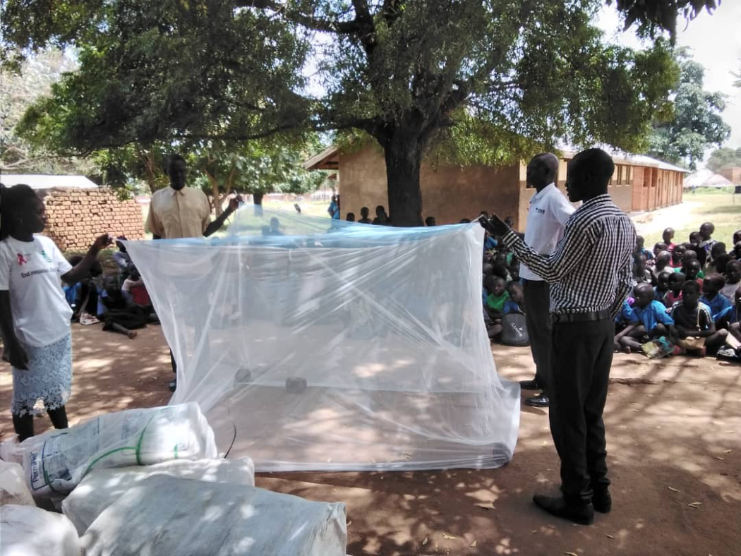Community health workers distribute bed nets to primary school students in Kitgum District, Uganda. Photo courtesy Malaria Consortium.