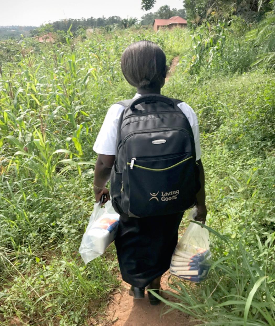 Harriet, a community health worker in rural Uganda, walks through her village carrying medicines and supplies. Photo by Judith Ssesse for Living Goods.