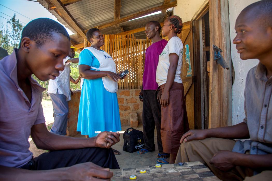 A Living Goods-supported community health worker uses mobile technology while talking to members of her community
