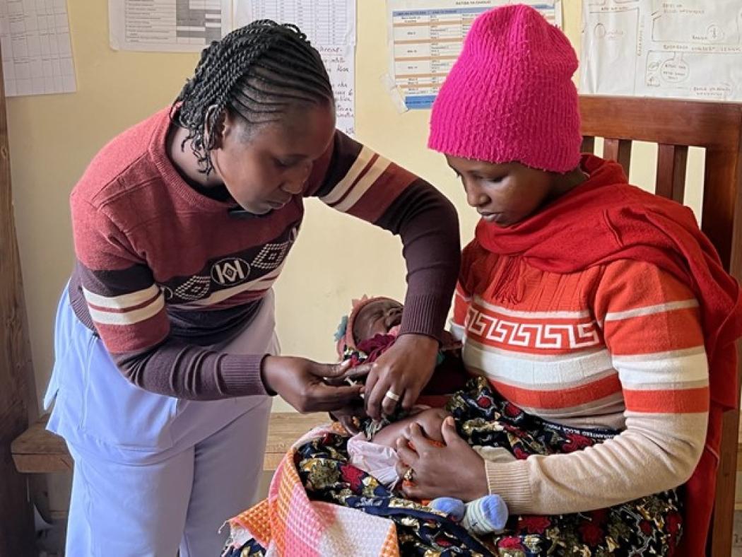 In Arusha, Tanzania, a young mother cradles her newborn baby as a nurse administers a pneumococcal vaccine. Photo by: Emily Bartels-Bland for Pathfinder International