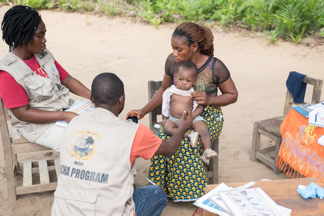 Community health supervisor Karana Weefar coaches community health workers Laura Gbee and Peter Zeo on how to count a young girl's respiration rate. Photo by Rachel Larson for Last Mile Health.
