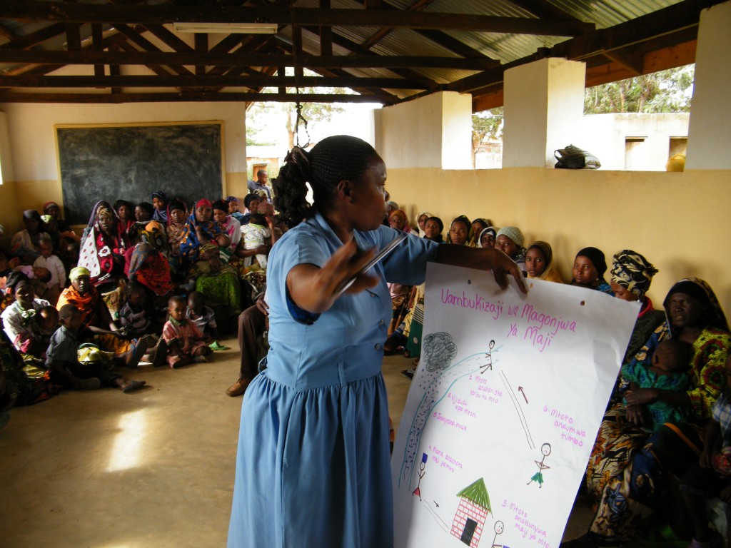 Tanzanian nurse Helena Michael teaches a group of young mothers about the transmission of waterborne diseases and how to make ORS solution for treatment of childhood diarrhea.